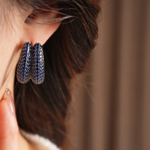 Close-up of model wearing U-shaped earring with deep blue zircon and sparkling crystals