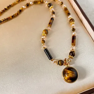 Macro shot of Maillard-style tiger eye stone necklace with gold-plated bezel pendant