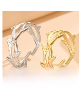 Close-up of gold and silver twig-shaped adjustable rings with textured branch detail