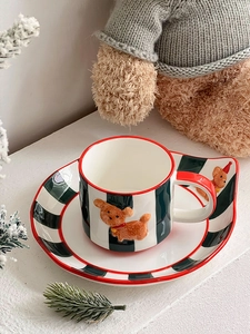 Detail of ceramic coffee mug and saucer set with festive hand-painted teddy bear motifs