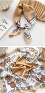 Detailed view of square silk scarf with gold chain and hot air balloon patterns