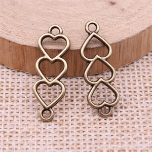 Detailed macro view of vintage bronze triple heart connector with dual hanging loops