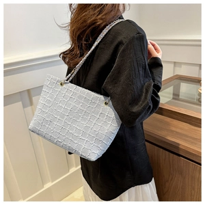 Detail of light blue tweed tote bag featuring silver chain strap on female model