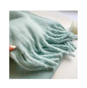 Close-up of soft light green mohair scarf showing fuzzy texture and fringe details