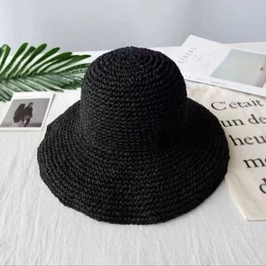 Dettaglio del cappello da spiaggia in paglia nera con trama intrecciata e tesa larga
