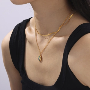 Elegant gold-layered necklace with blue oval pendant and snake chain on model