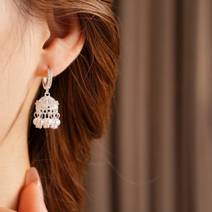 Close-up of zircon bell tassel pearl earrings in silver finish on a model's ear