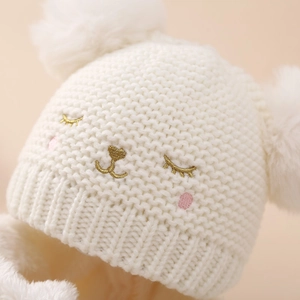 White baby knitted hat with twin pom-poms and cute animal face embroidery