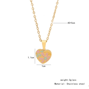 Detailed close-up of gold stainless steel heart pendant with floral enamel patterns