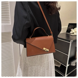 Brown crocodile-embossed mini crossbody bag with gold-tone twist lock on model