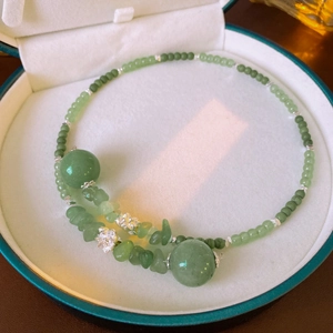 Dettaglio di perle di giada verde e ciondoli a loto in argento in una scatola portagioie