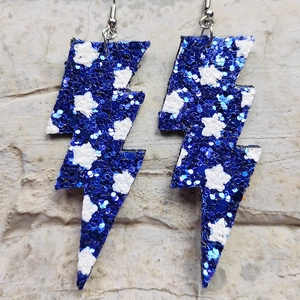 Dettaglio di orecchini a saetta con glitter blu e motivi a stella bianca