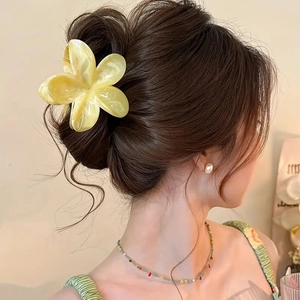 Detailed side view of large yellow plumeria hair claw clip in a sweet floral hairstyle