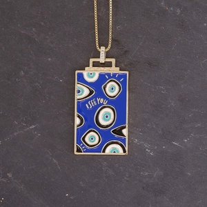 Macro shot of gold rectangle pendant with blue enamel devil eye and I SEE YOU text