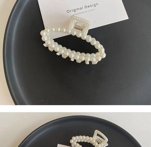 Detailed view of elegant faux pearl hair claw clips on a minimalist black display plate