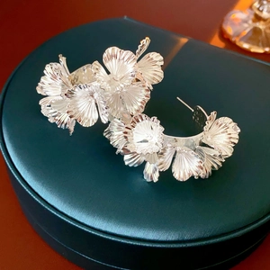 Detail shot of silver flower earrings with layered petals on a green jewelry box