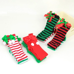 Close-up of festive over-knee Christmas socks with striped patterns, bows, and pom-poms