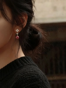 Close-up of a model wearing 18K gold plated zircon flower earrings with red resin beads
