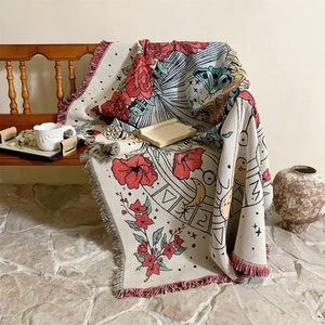 Close-up of bohemian woven blanket with floral and celestial patterns and colorful tassels