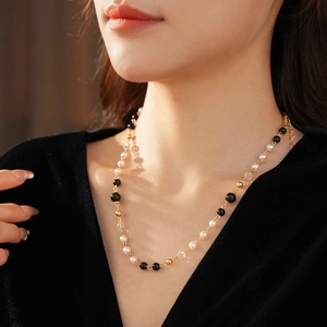 Gros plan sur un collier de perles rétro avec agates noires et fermoir doré chic
