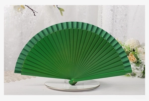 Classic green wooden folding fan opened on white lace cloth with floral decorations