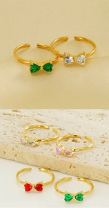 Dettaglio anello a fiocco dorato con zirconi colorati a cuore su base in pietra di lusso