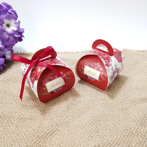 Detail of red bread-shaped wedding candy box with floral patterns and a silk ribbon
