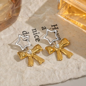 Orecchini a fiocco in oro 18K e acciaio argento con cristalli su carta con texture