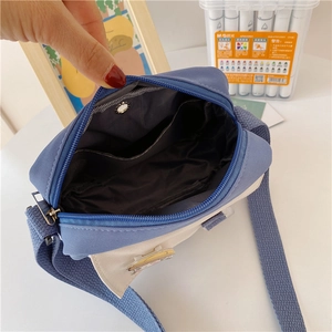 Interior detail of a blue and beige canvas crossbody bag with nylon lining and inner pocket