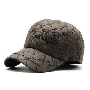 Detail of brown quilted baseball cap featuring diamond stitching and metal brand plaque