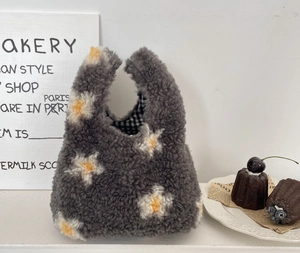 Détail du sac à main en peluche grise avec fleurs marguerites et doublure à carreaux