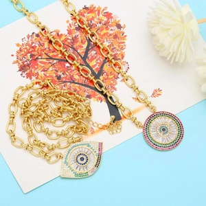 Detail of chunky gold chain necklaces featuring multi-color evil eye crystal pendants
