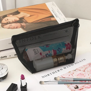 Minimalist black mesh makeup bag with zipper shown in a stylish tabletop setting