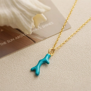 Collier doré avec pendentif corail turquoise sur un fond beige texturé élégant