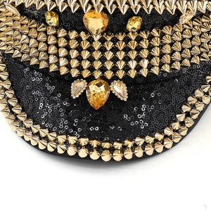 Detailed view of black sequin captain hat featuring gold metal spikes and yellow gemstones