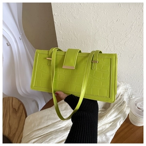 Detail of green faux crocodile leather handbag with golden buckle and twin straps