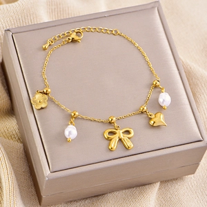 Detail van armband met strik-, hart- en parelhangers getoond op een sieradendoos