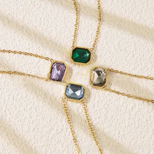 Detail of four emerald-cut crystal necklaces in green, purple, clear, and blue with gold chains