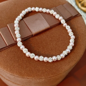 Detail of pink pearl bracelet with pavé crystal beads on brown velvet jewelry box lid