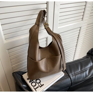 Detailansicht der braunen Ledertasche mit Ziernähten auf einem Tom Ford Buch platziert