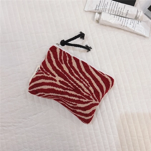 Close-up of zebra pattern knitted coin purse with a sturdy zipper and hand cream