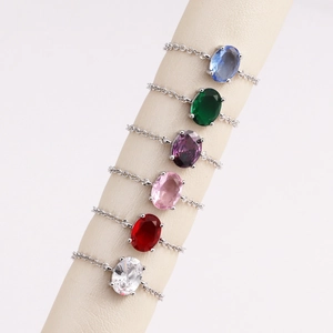 Detail of colorful oval zircon stone rings with silver chain bands on beige stands