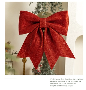 Close-up of a large red glitter bow hanging on a green Christmas tree branch