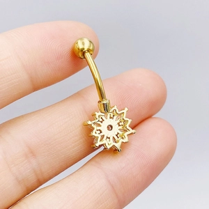 Close-up of golden stainless steel navel ring featuring a sparkling zircon snowflake charm