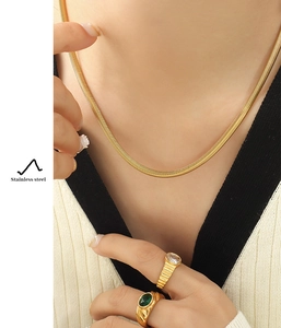 Detailopname van gouden slangenketting en edelsteenringen bij een model