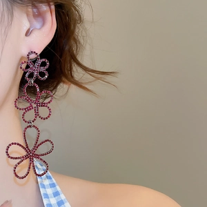 Macro shot of three-tier red rhinestone hollow flower tassel drop earrings on model