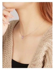 Macro detail of 925 sterling silver necklace with pink floral zircon pendant on neck