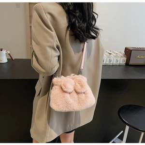 Close-up of pink plush bunny bucket bag worn by model with leather strap detail