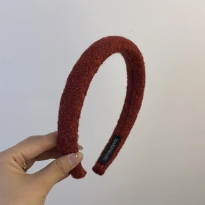 Close-up of a reddish-brown tweed padded headband with handmade label detailing