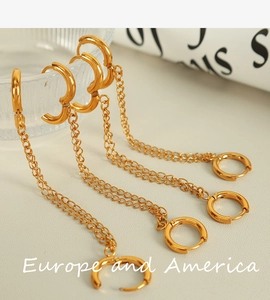 Detailed macro view of gold hoop earrings with connecting chains on a textured surface